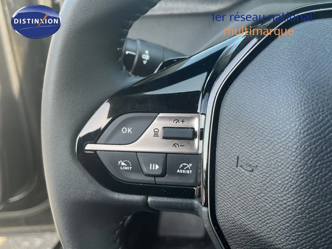 Détail du volant noir de la Peugeot 408 1.2 Hybrid 145ch avec commandes intégrées et finition brillante.