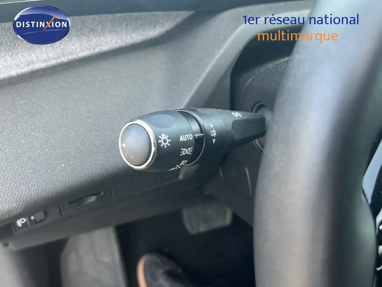 Gros plan sur la commande des phares à gauche du volant d’un Peugeot 408 noir métal, intérieur moderne.
