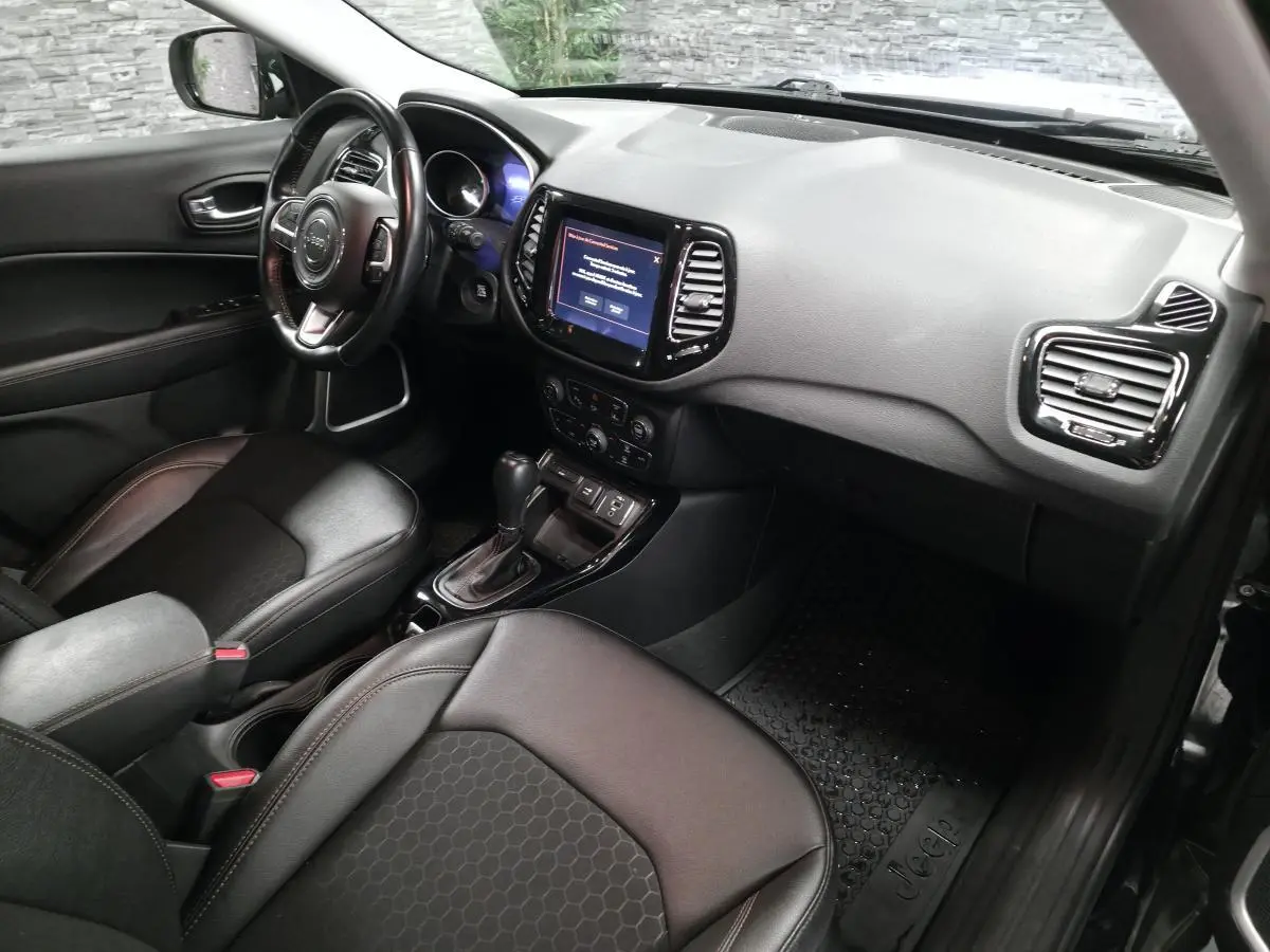 Vue intérieure côté conducteur du Jeep Compass 2021 avec sellerie simili cuir noire et écran tactile central.