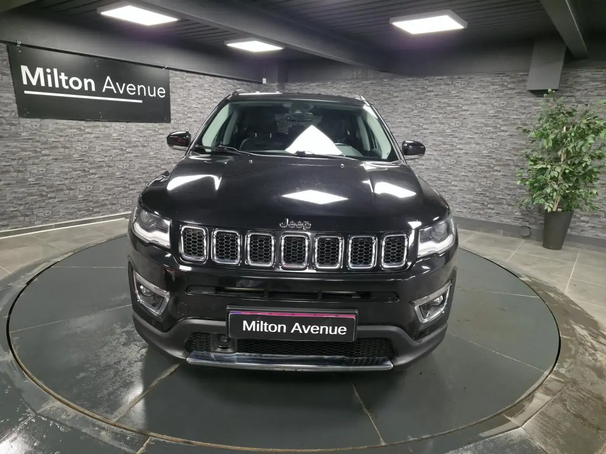 Vue de face du Jeep Compass noir 2021 avec calandre chromée et projecteurs LED dans un showroom.
