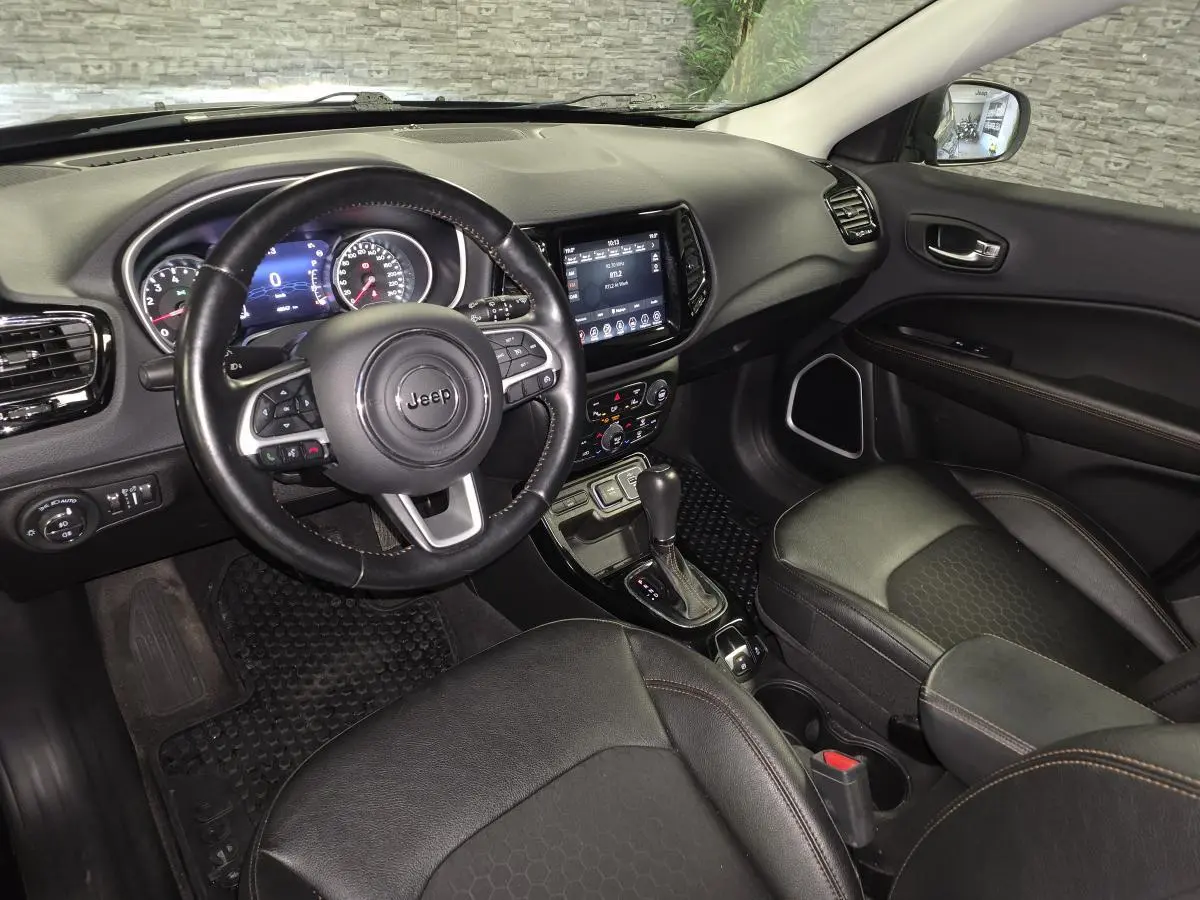 Intérieur avant droit du Jeep Compass noir 2021, volant cuir, écran tactile central et sièges simili cuir.