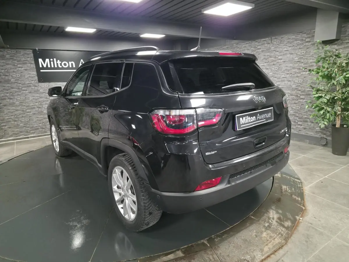 Jeep Compass noir en 3/4 arrière droit dans un showroom avec jantes alliage 18 pouces et vitres surteintées.