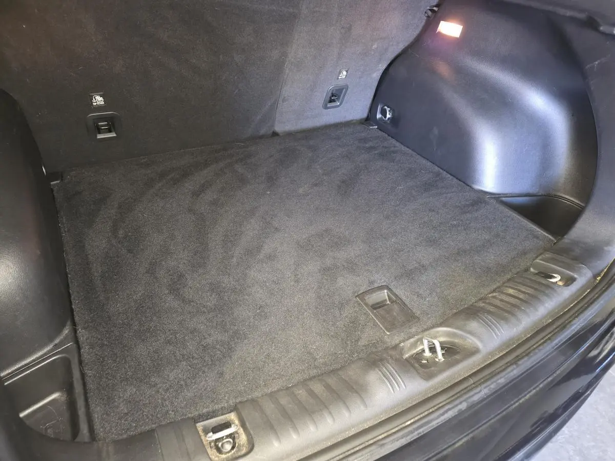 Coffre vide vu de l'arrière d'un Jeep Compass noir 2021 avec tapis de sol en caoutchouc et éclairage intérieur.