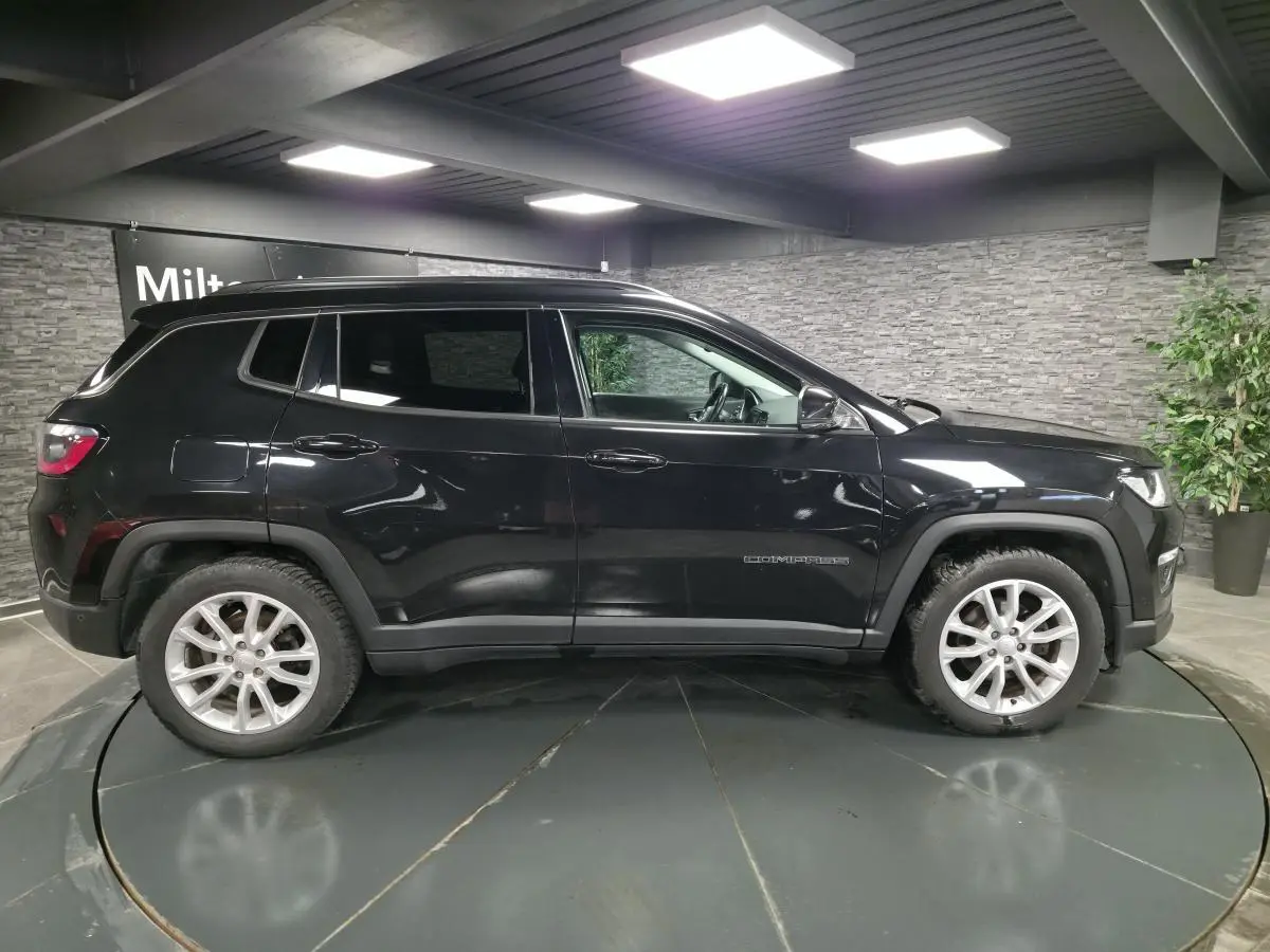 Vue de profil côté gauche d'un Jeep Compass noir, avec jantes alliage 18 pouces et vitres surteintées.