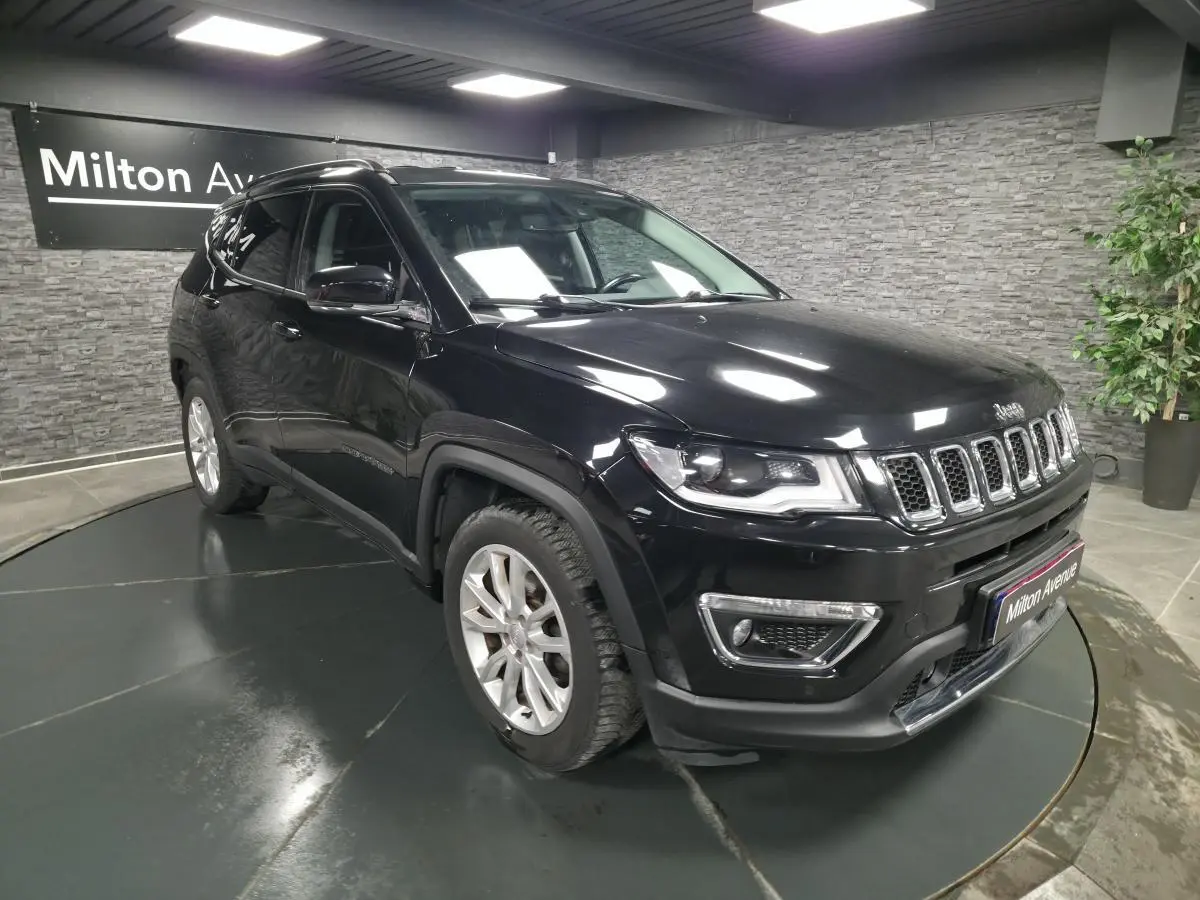 Jeep Compass noir en 3/4 avant droit, avec calandre chromée et jantes alliage 18 pouces visibles en intérieur showroom.