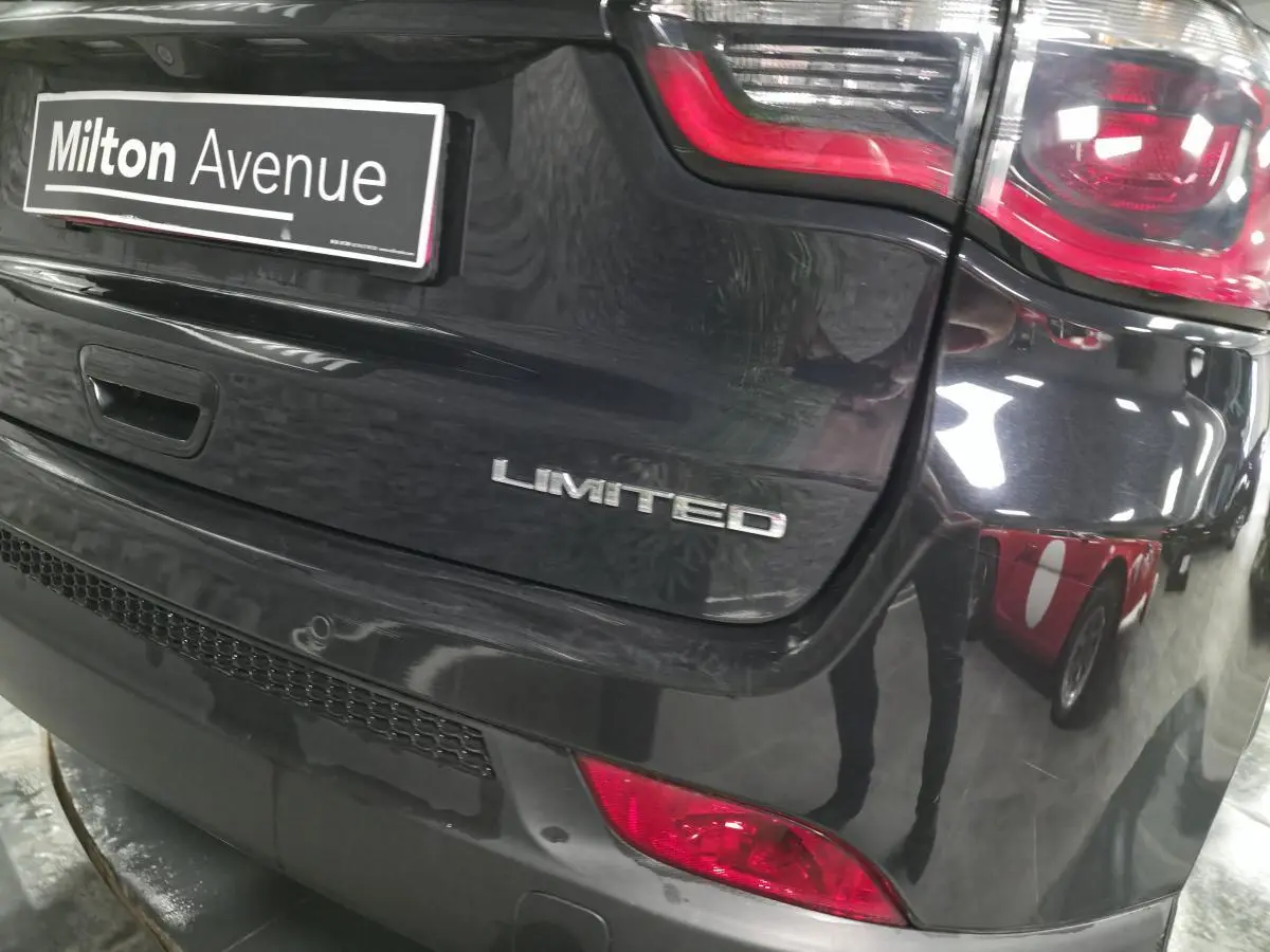 Gros plan sur l'arrière droit noir brillant d'un Jeep Compass Limited avec feux rouges et logo visible.