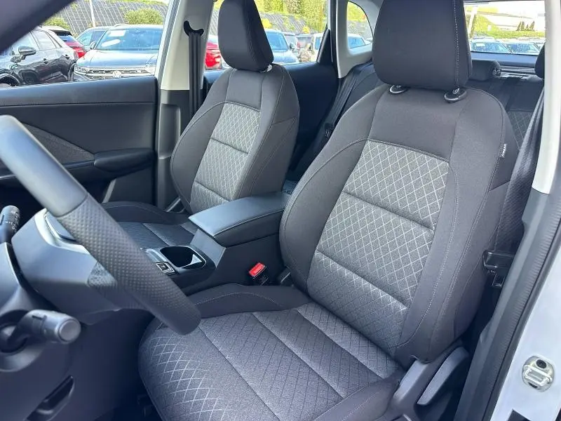 Vue intérieure côté conducteur du MG ZS Hybrid+ 2025, sièges tissu noir avec motifs losanges et accoudoir central.