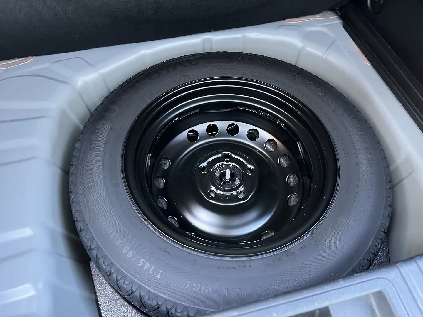 Pneu de secours noir en gros plan dans le coffre d’un Renault Captur gris Rafale toit noir 2025.