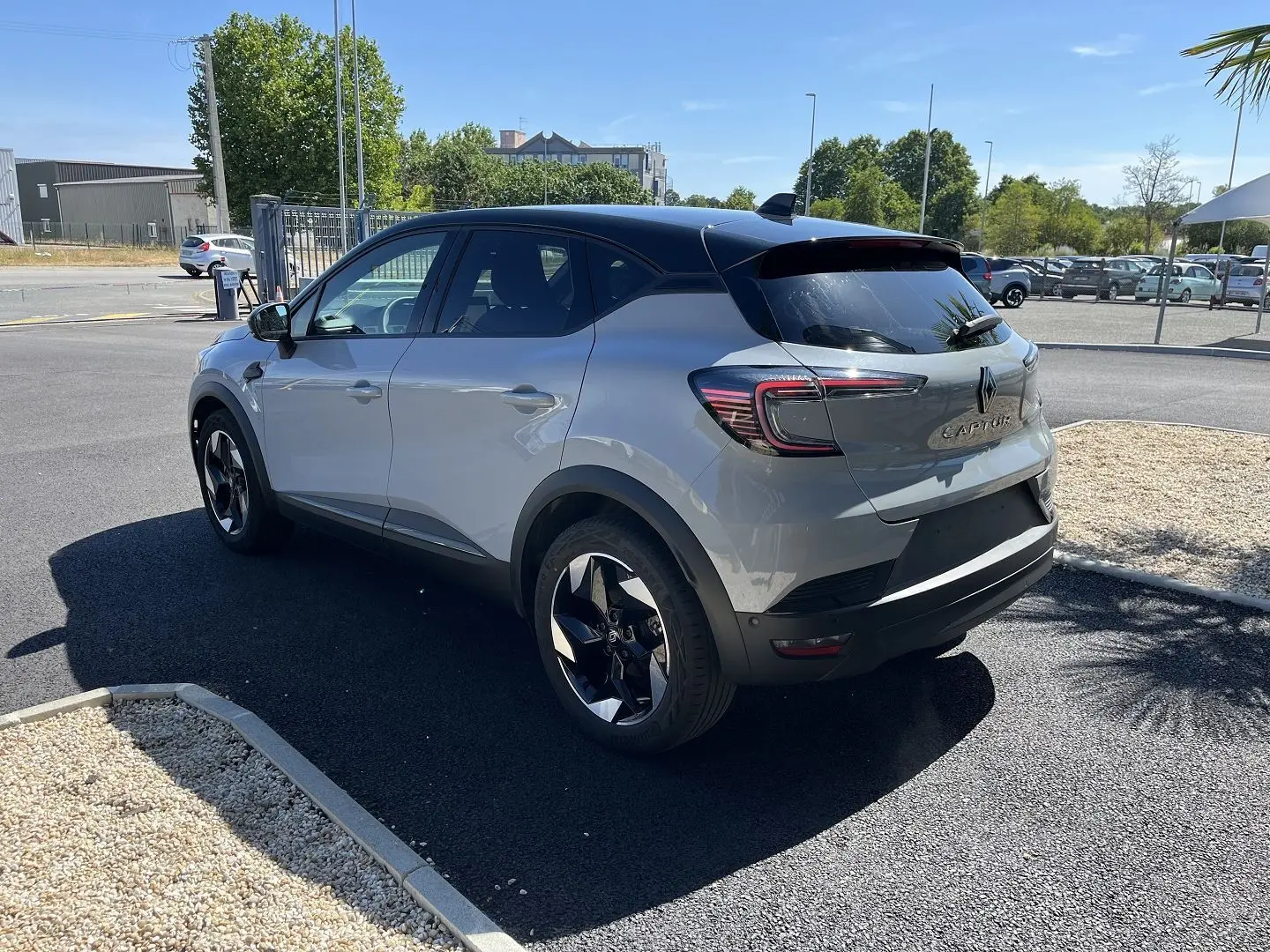 Vue 3/4 arrière droite du Renault Captur 2025 gris Rafale avec toit noir et jantes noires bicolores.