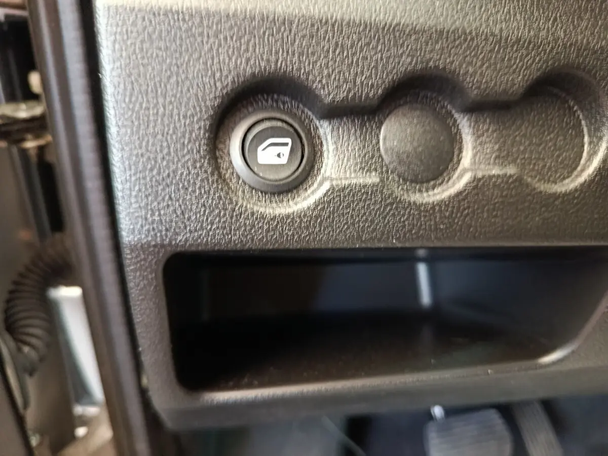 Gros plan sur le bouton de commande de vitre électrique dans l’habitacle gris foncé de l’AIXAM Ambition 0.5 City Crossline Pack 2026.