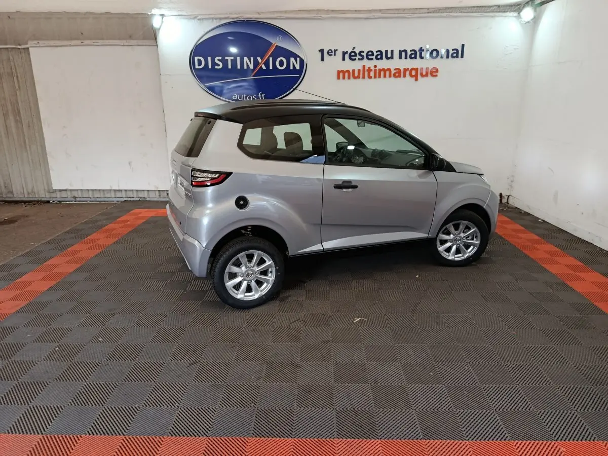 Vue de profil côté gauche d'une Aixam Ambition 0.5 City Crossline Pack gris foncé avec toit noir en intérieur showroom.