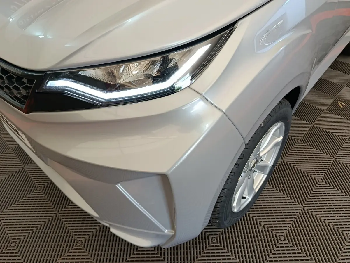 Gros plan sur l'avant droit gris foncé de l'AIXAM AMBITION 0.5 CITY CROSSLINE PACK 2026 avec phare LED allumé.