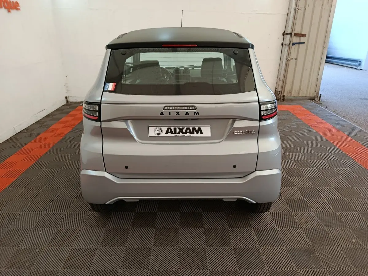 Vue arrière d'une Aixam Ambition gris foncé 2026 avec toit noir, feux arrière modernes et logo distinctif au centre.