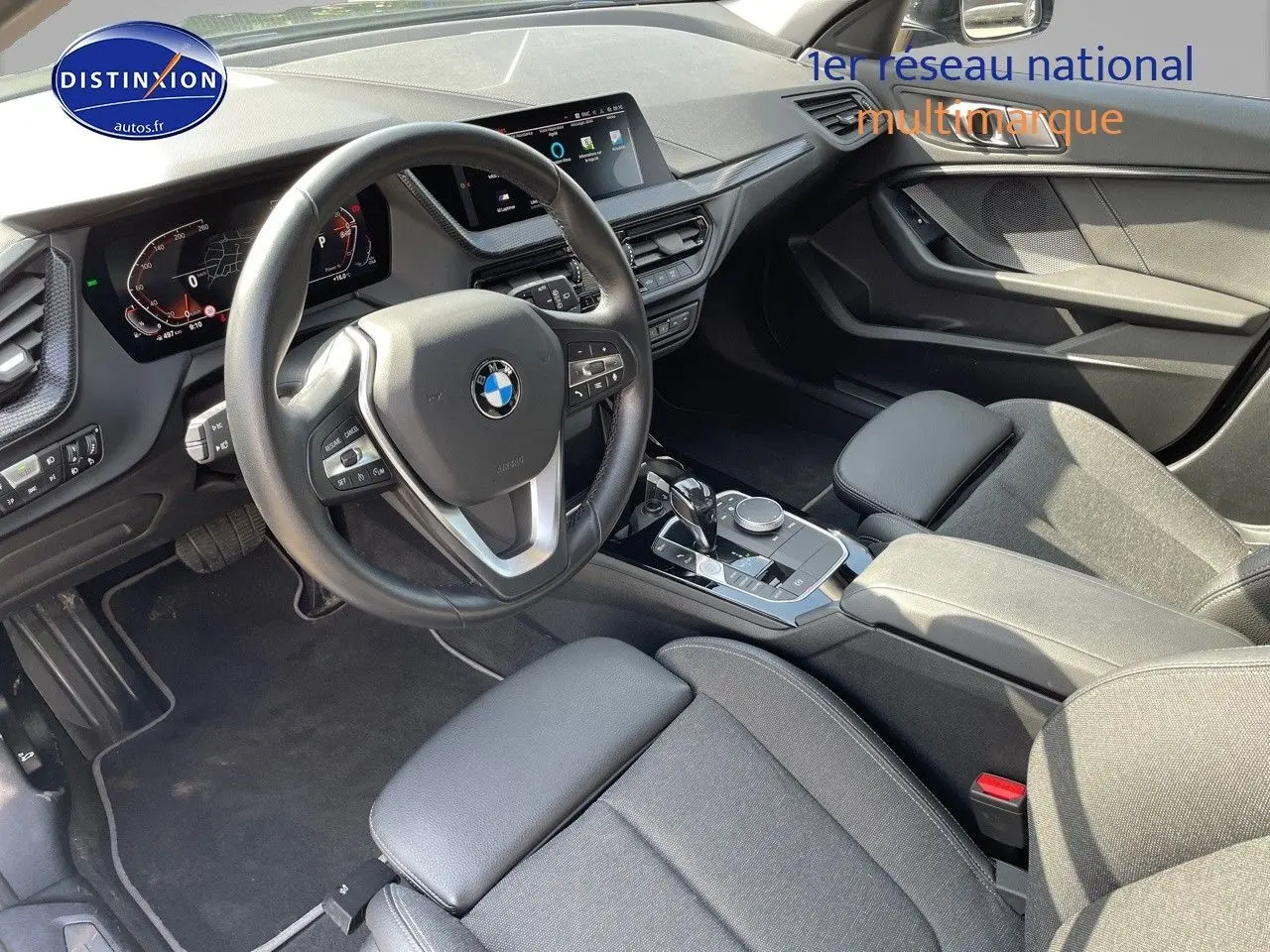 Intérieur BMW Série 1 118i 2021 vu côté conducteur, volant cuir, tableau de bord digital et console centrale moderne.