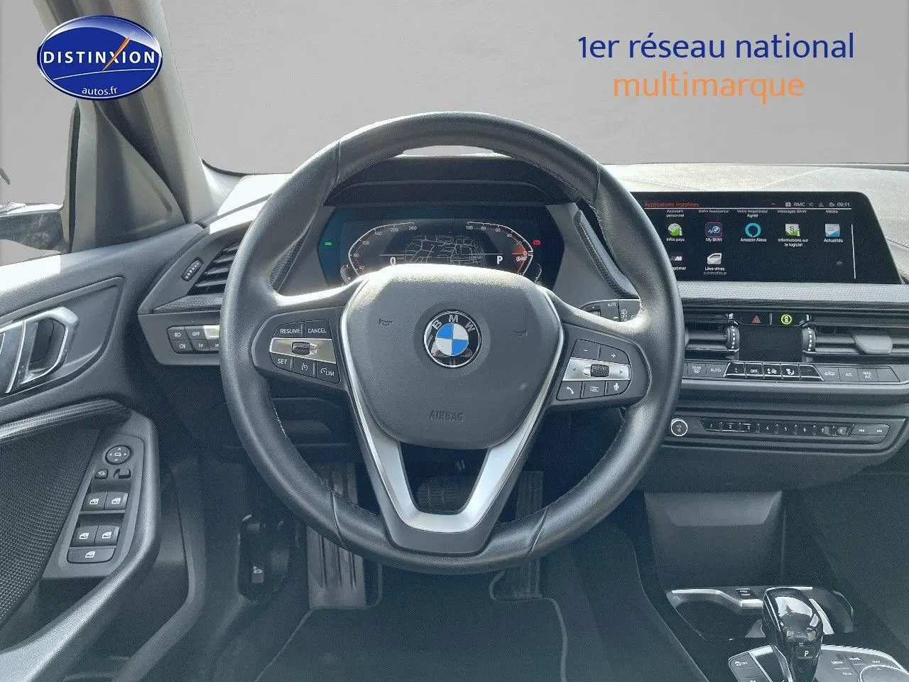 Vue frontale de l'intérieur de la BMW Série 1 118i 2021, volant cuir noir et tableau de bord digital lumineux.