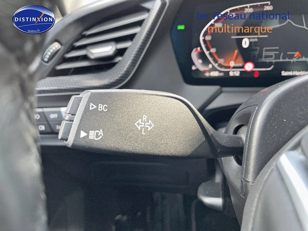 Le levier de clignotant gauche de la BMW Série 1 118i 2021 gris minéral, avec tableau de bord numérique en arrière-plan.