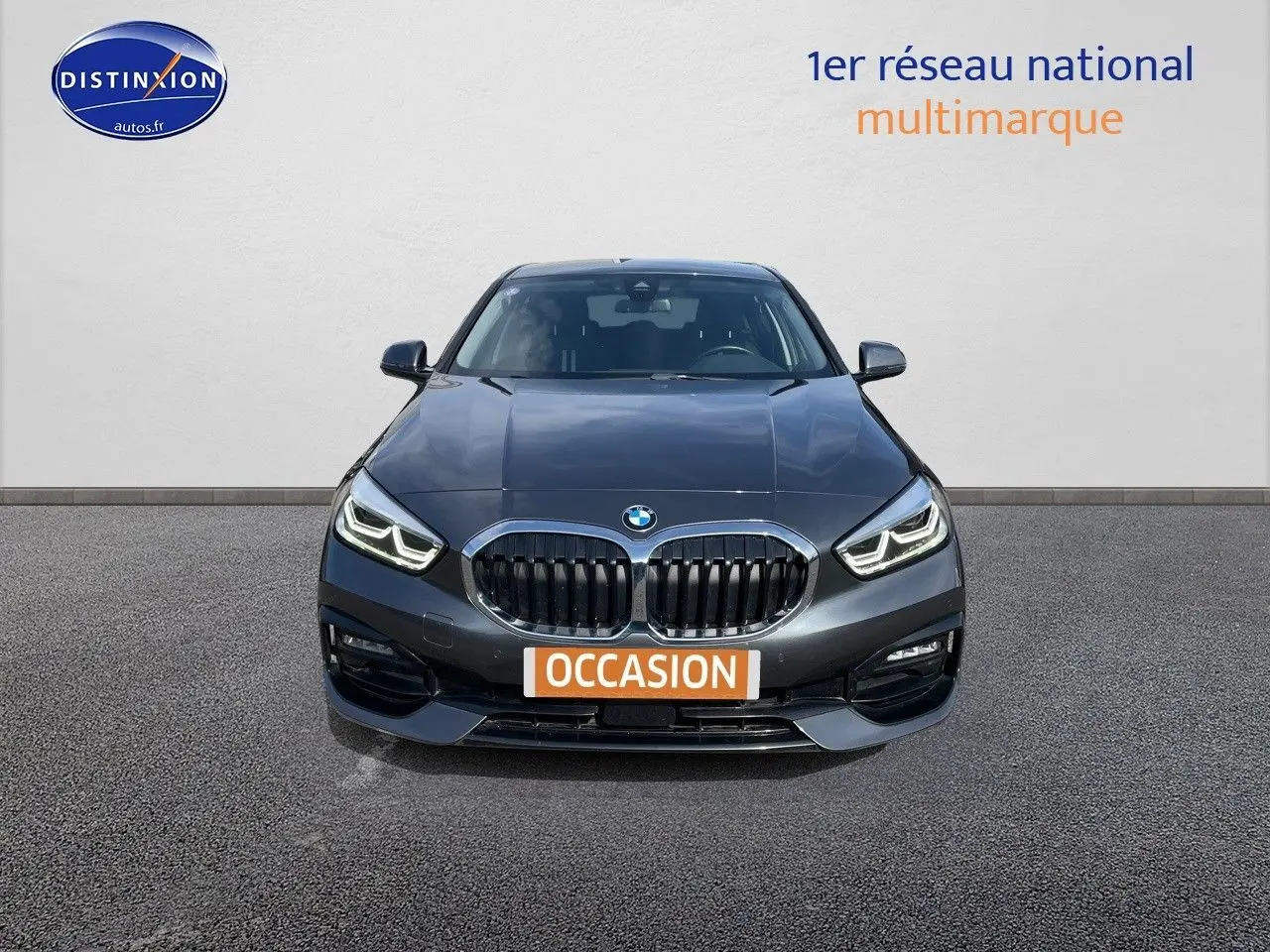 Vue frontale d'une BMW Série 1 gris minéral métal avec calandre double haricot et phares LED allumés.