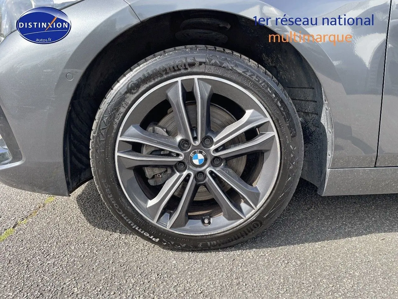 Gros plan sur la roue avant gauche gris minéral métal d'une BMW Série 1 118i Edition Sport avec jante alliage bi-ton.