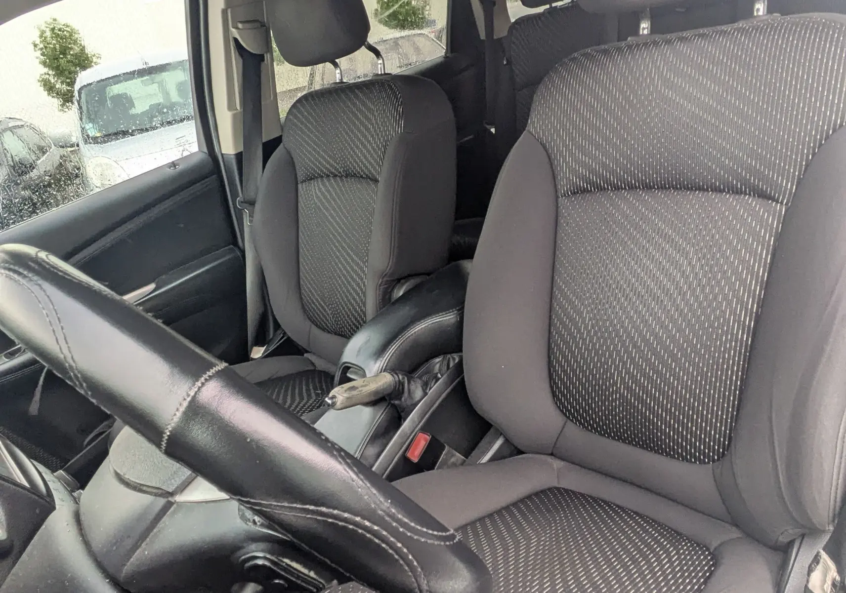 Vue 3/4 arrière droite d'un FIAT Freemont gris avec barres de toit et vitres arrière surteintées.