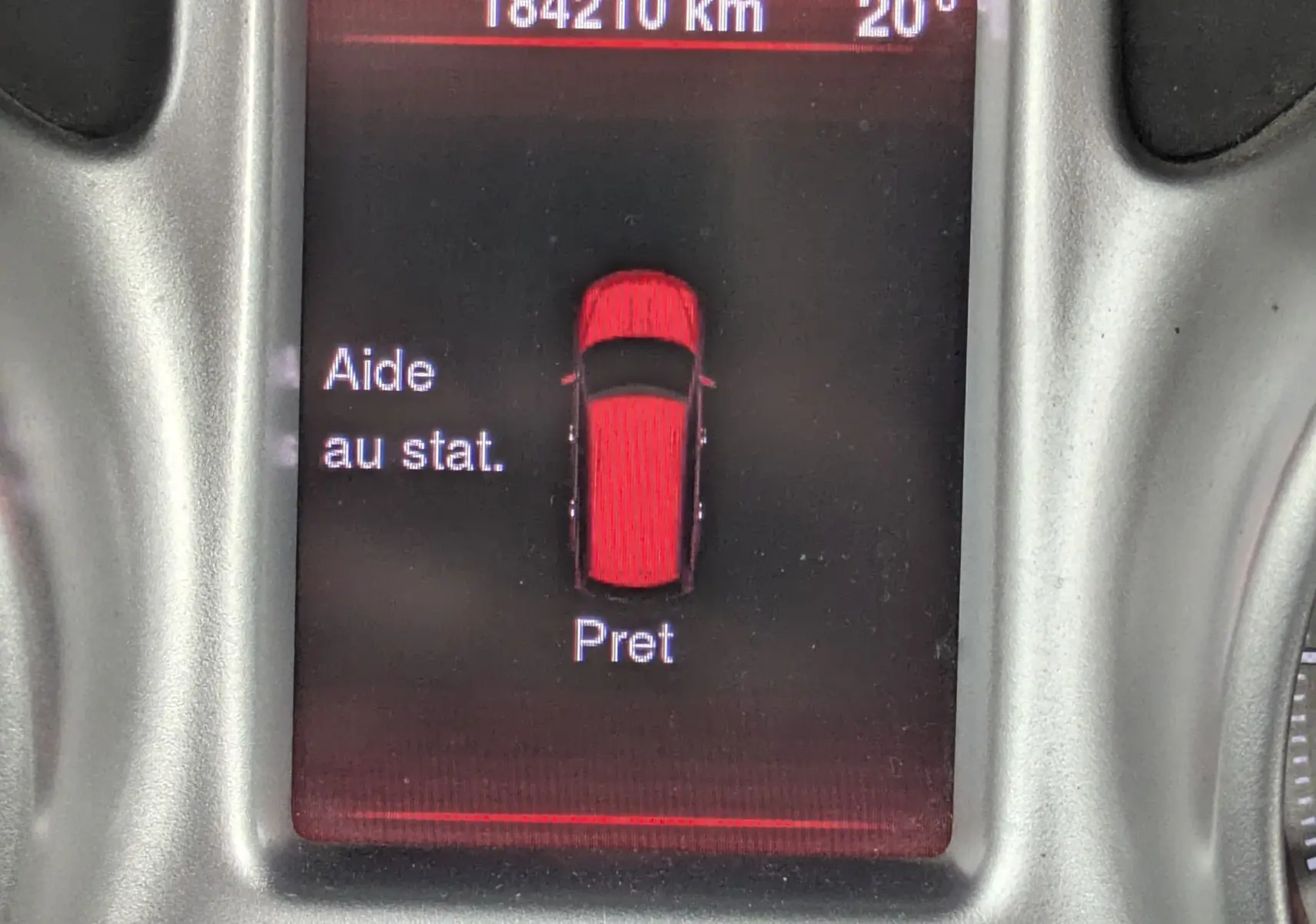 Vue 3/4 avant droit d'un FIAT Freemont gris avec barres de toit dans un showroom blanc.