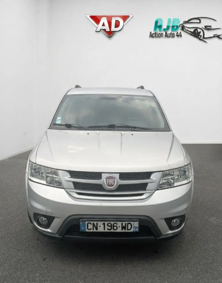 Coffre ouvert vu de l'arrière d'un FIAT Freemont gris, montrant l'espace de chargement et la banquette arrière noire.