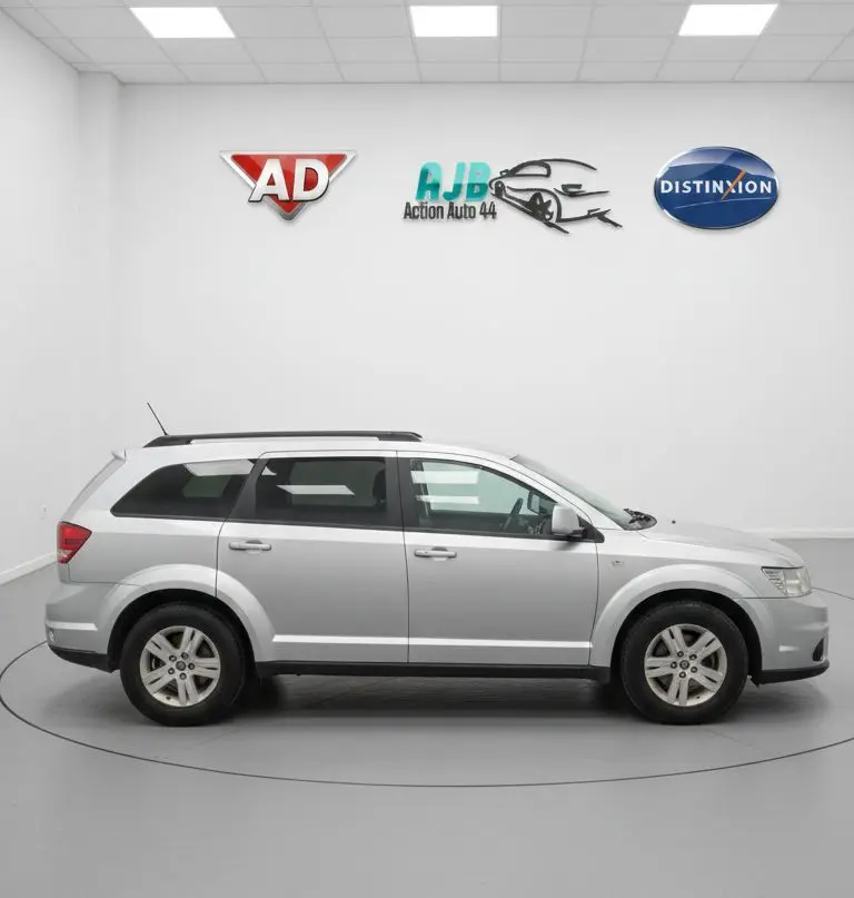 Vue intérieure côté conducteur du Fiat Freemont gris, montrant les sièges avant noirs et le volant cuir.