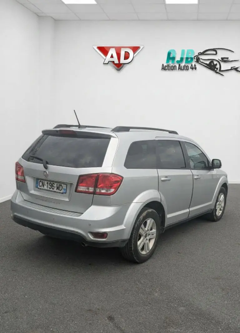 Vue rapprochée du tableau de bord noir du Fiat Freemont 2012, avec écran tactile affichant radio et commandes climatisation.