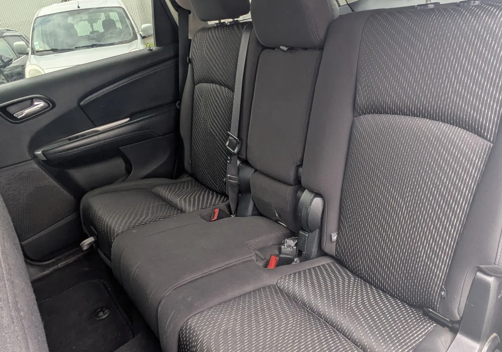 Vue de profil côté gauche d'un FIAT Freemont gris avec barres de toit et jantes alu dans un studio blanc.