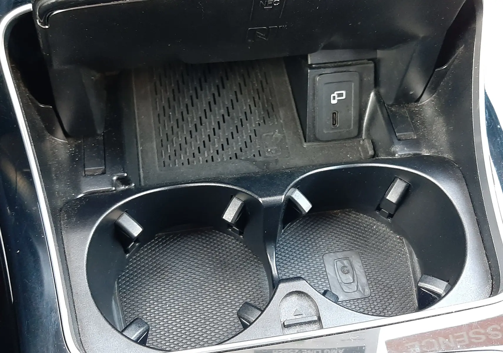 Gros plan sur la console centrale noire du Mercedes GLC Coupé blanc, montrant porte-gobelets et prise USB.