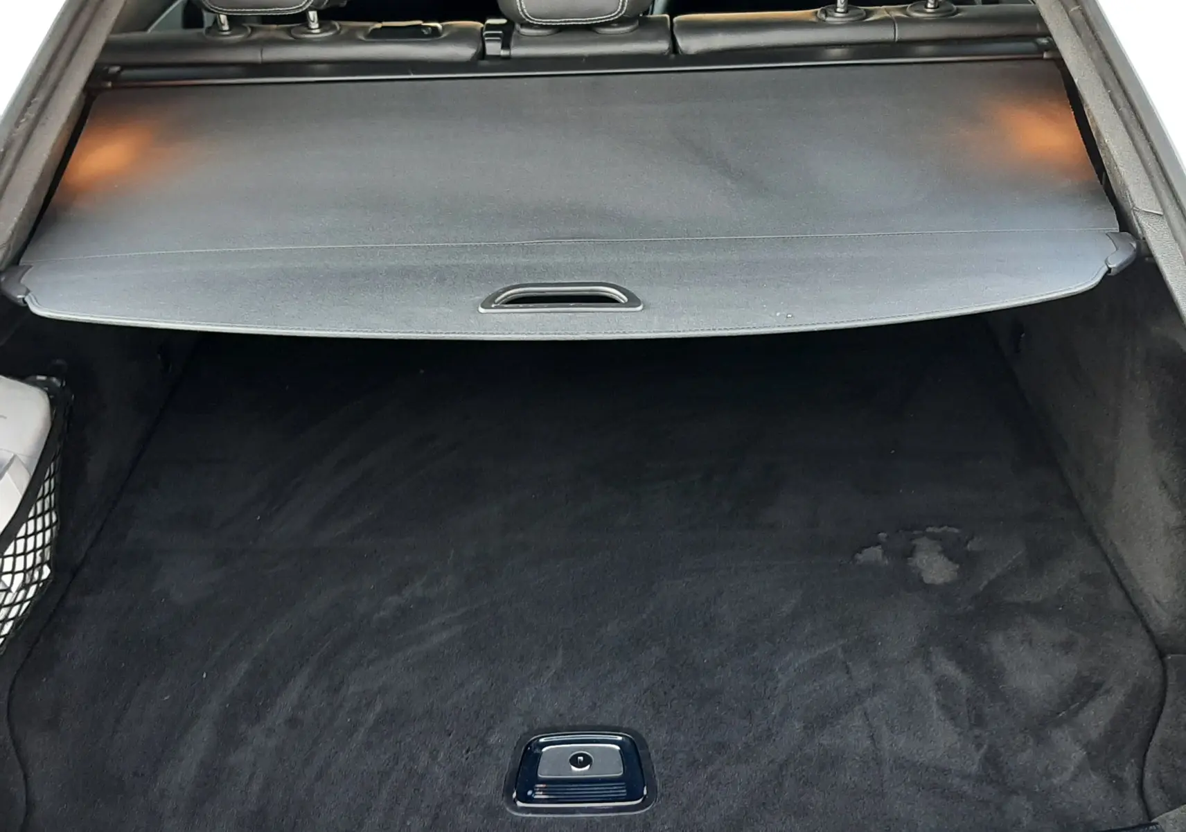 Coffre ouvert vu de l'arrière d'un Mercedes GLC Coupé blanc, avec cache-bagages et intérieur noir visible.