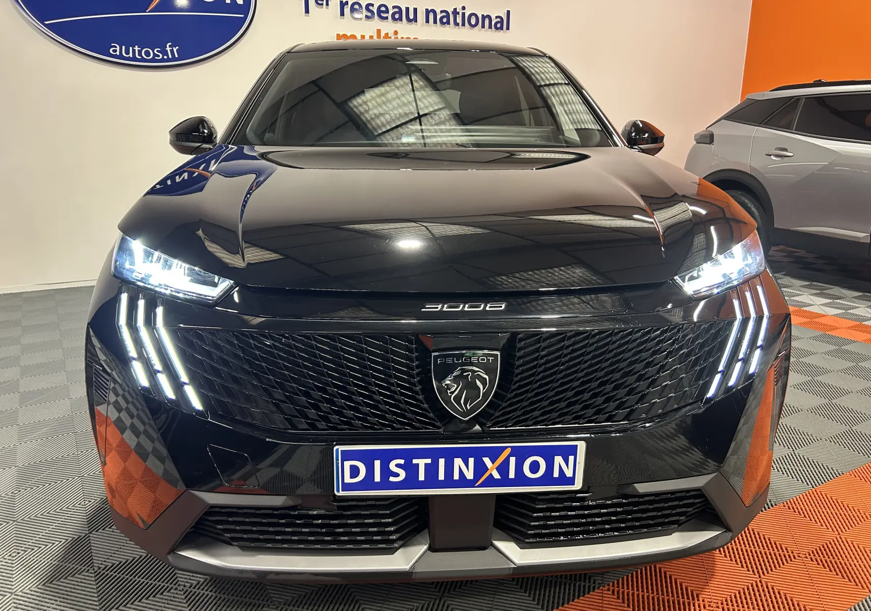 Vue avant du Peugeot 3008 III Hybrid noir avec phares LED allumés et calandre au lion distinctif.