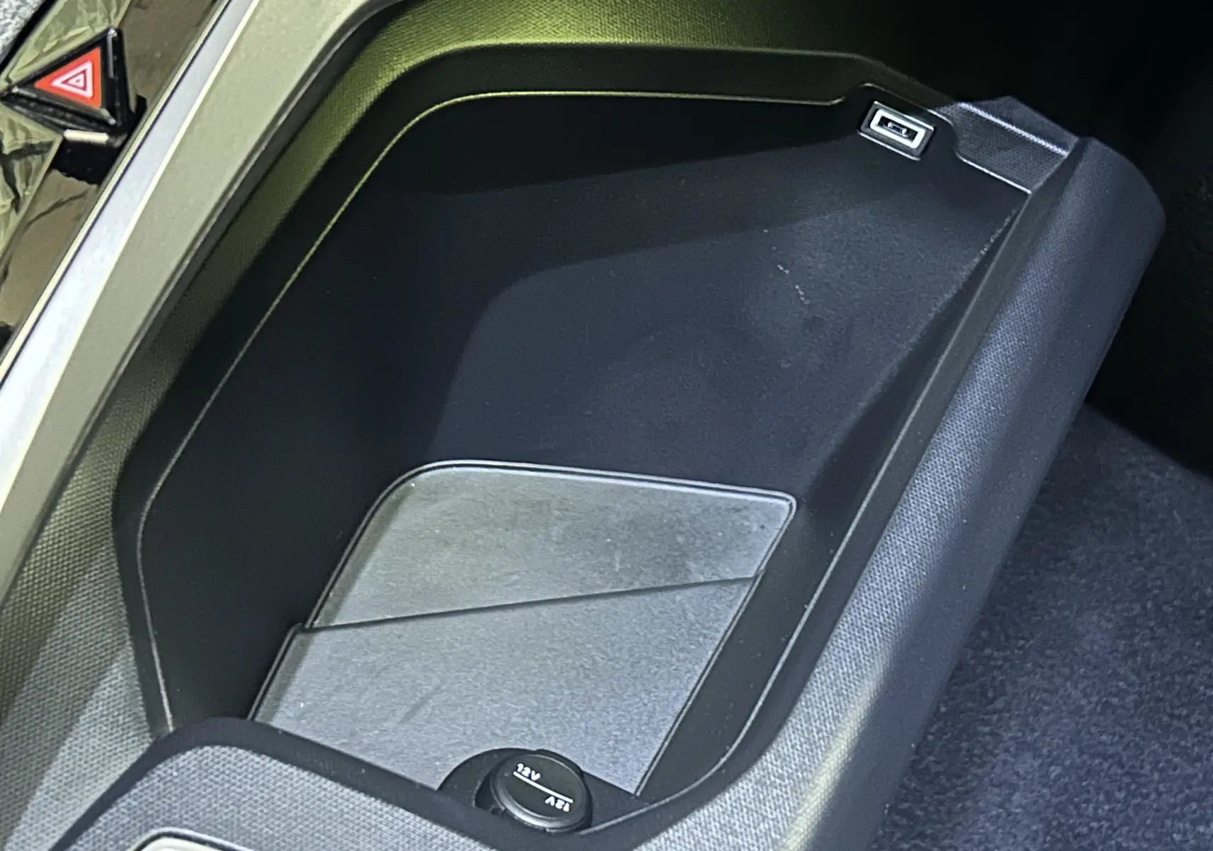 Gros plan sur le rangement central noir avec prise USB et prise 12V dans le Peugeot 3008 hybride 2025.