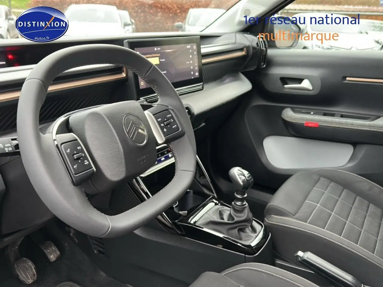 Intérieur avant gris du Citroën C3 Aircross 2025, volant multifonction, écran tactile et levier de vitesses manuel visible.