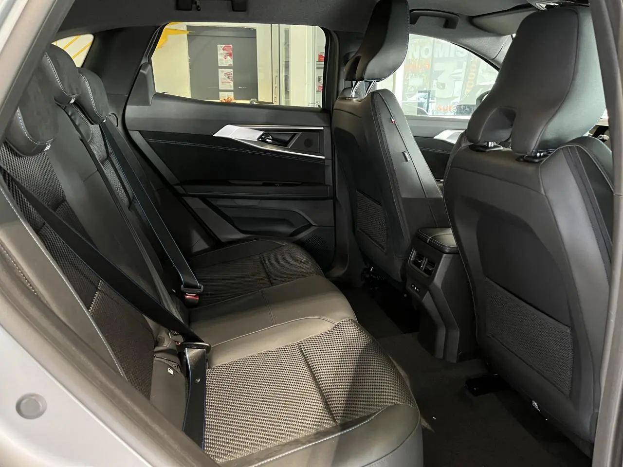 Vue intérieure côté gauche des sièges arrière gris avec sellerie mixte tissu carbone Alcantara et surpiqûres bleues du Renault Austral 2025.