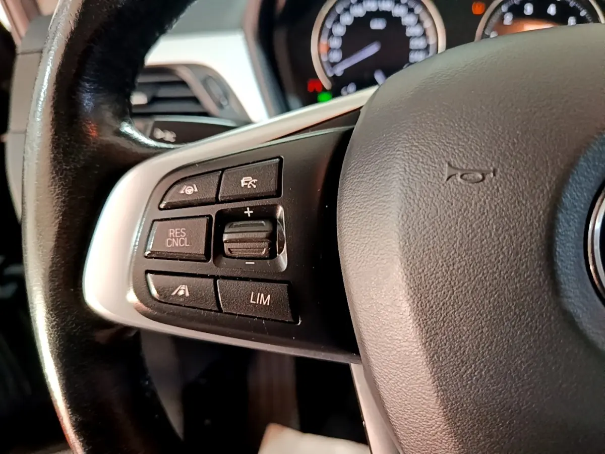 Gros plan sur le volant cuir noir de la BMW X1 2020, avec commandes du régulateur de vitesse sur le côté gauche.