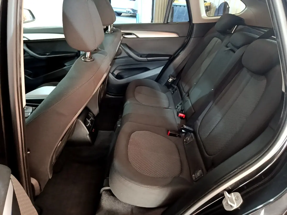 Vue intérieure côté droit sur la banquette arrière noire du BMW X1 sDrive20i Business Design 2020, sièges tissu et appuie-têtes visibles.