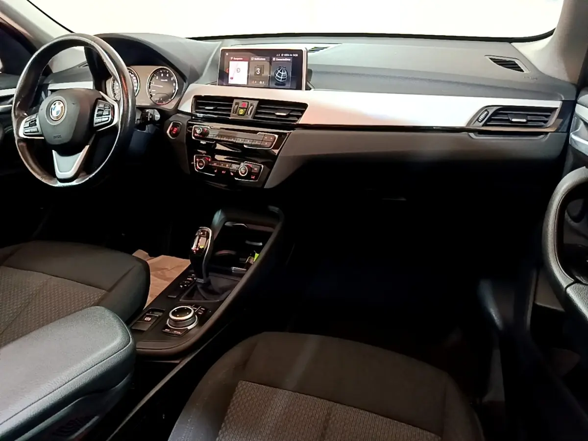 Intérieur noir de BMW X1 2020, vue côté conducteur sur tableau de bord avec écran tactile et volant cuir multifonctions.