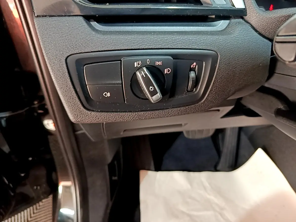 Gros plan sur le panneau de commande des phares noir dans l'habitacle d'une BMW X1 sDrive20i 2020.