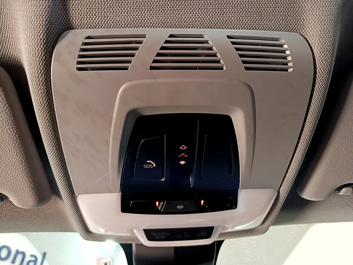 Vue en contre-plongée du plafonnier gris clair avec commandes SOS et éclairage intérieur d'une BMW X1 noire de 2020.