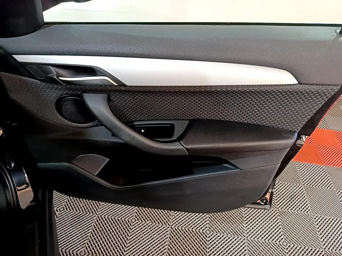 Vue intérieure du panneau de porte arrière gauche noir de la BMW X1 sDrive20i Business Design 2020 avec insert tissu et poignée intégrée.