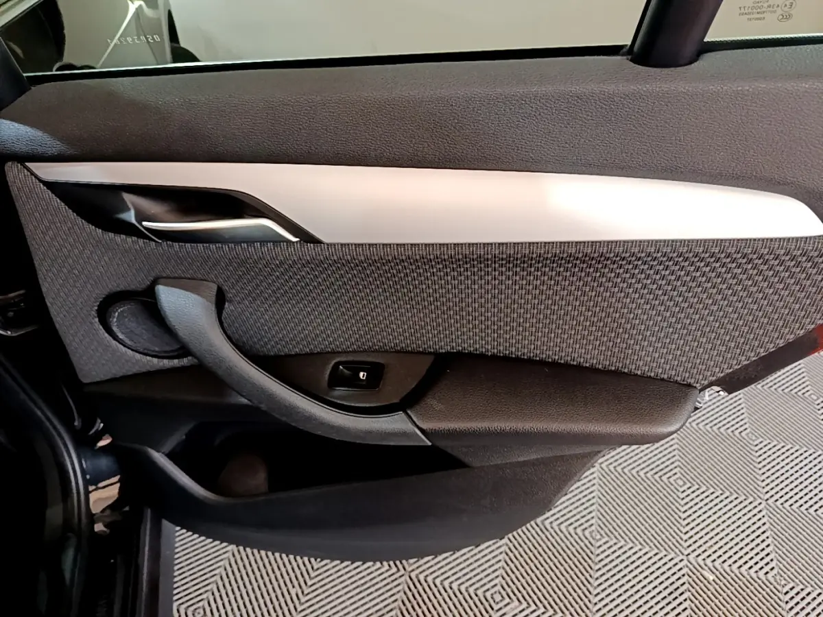 Vue intérieure côté gauche de la porte arrière noire du BMW X1 2020 avec garniture tissu et poignée intégrée.