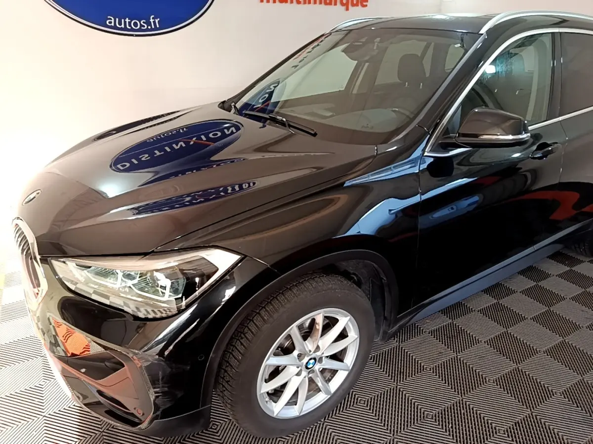 BMW X1 sDrive20i noir en 3/4 avant droit, mettant en valeur ses phares LED et jantes alliage argentées.