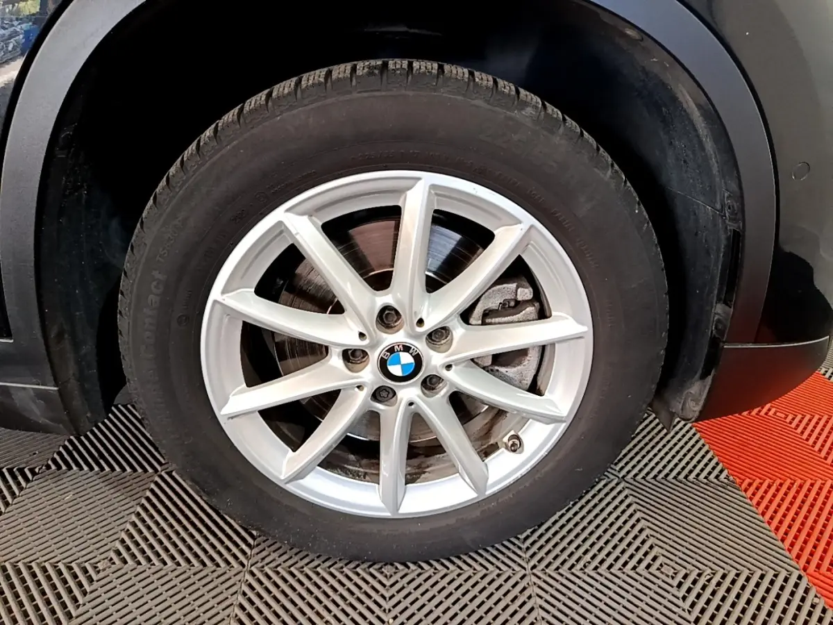 Gros plan sur la roue avant droite d’un BMW X1 noir, mettant en valeur la jante alliage argentée à 10 branches.