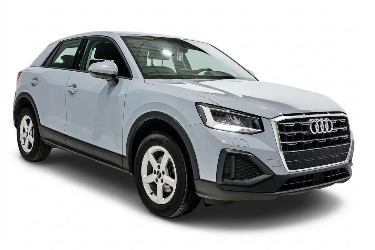 Audi Q2 gris vue 3/4 avant droit, avec calandre distinctive et phares LED allumés sur fond blanc.