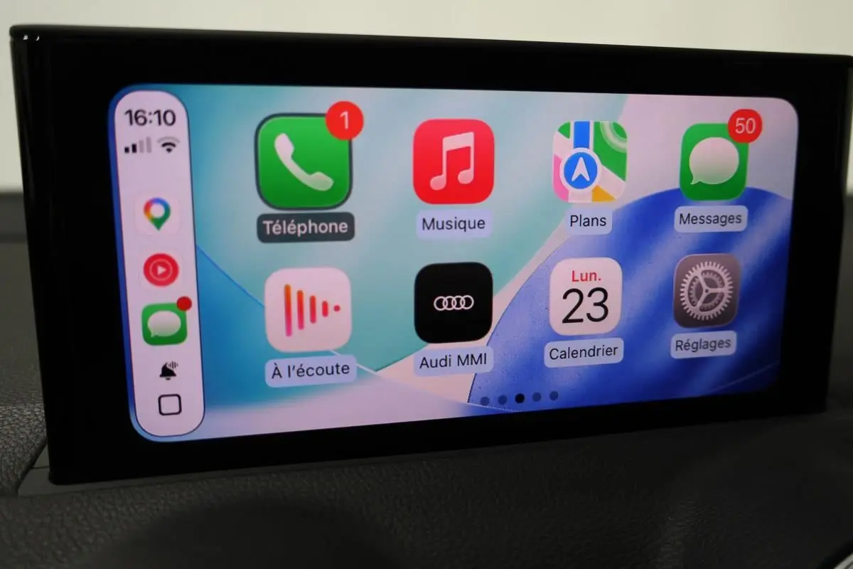 Écran tactile intérieur affichant l’interface Audi MMI avec applications GPS, téléphone et musique, vue de face.