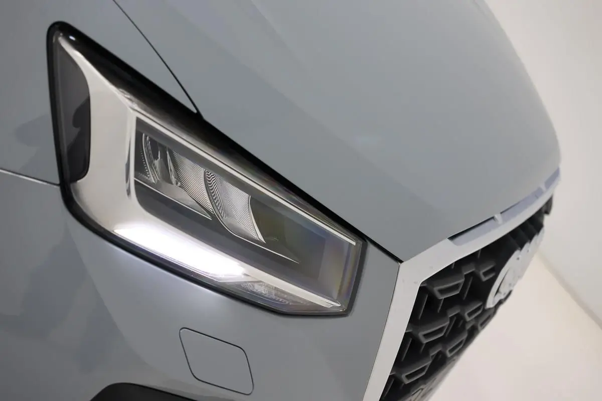 Gros plan sur le phare avant droit gris d'un Audi Q2 2023, mettant en valeur la calandre hexagonale et les lignes nettes.
