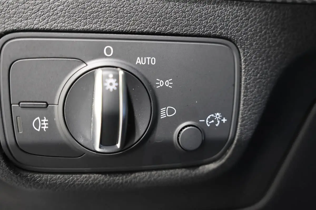 Gros plan sur le bouton de commande des phares de l'Audi Q2 gris, situé sur le tableau de bord côté conducteur.