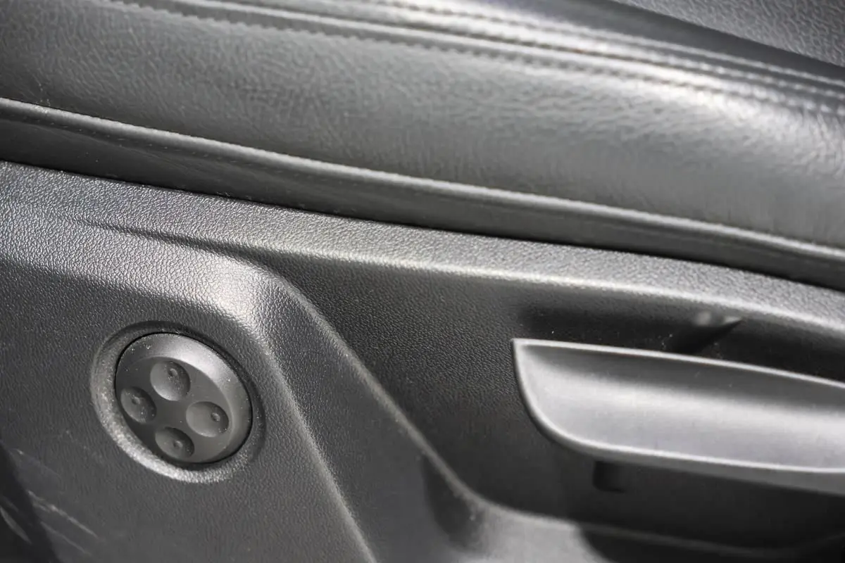 Détail des commandes de réglage du siège en cuir noir de l'Audi Q2 TFSI 110 gris, vue intérieure côté conducteur.