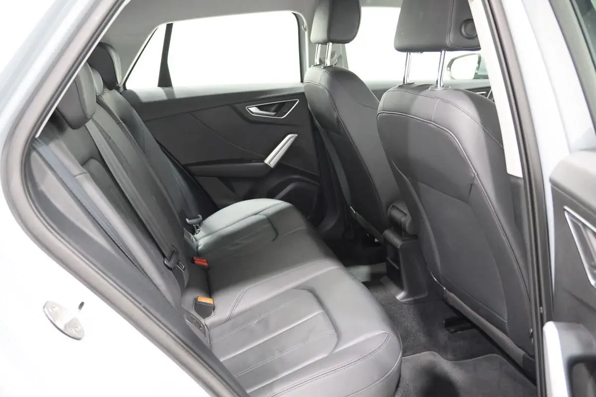 Vue intérieure côté gauche montrant les sièges arrière en cuir noir de l'Audi Q2 TFSI 110 gris de 2023.