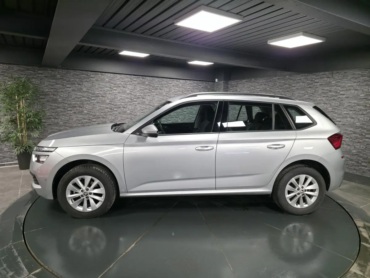 Vue de profil côté gauche d’un Skoda Kamiq gris métallisé 2023 en intérieur avec jantes alliage 16 pouces.